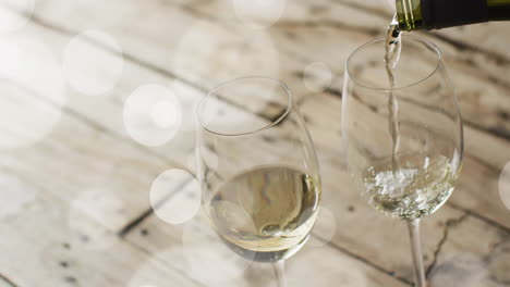 composite of white wine being poured into glasses on wooden surface