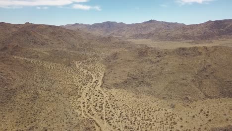 Luftdrohnenaufnahme-Der-Trockenen-Wüste-Im-Joshua-Tree-National-Park-Während-Eines-Sonnigen-Tages-Mit-Blauem-Himmel-In-Kalifornien,-USA