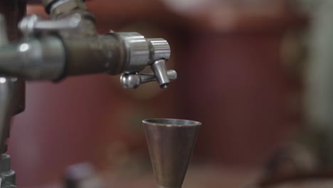 drips of ouzo, anise-flavored national drink of greece straight from the distiller tasting tap