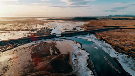 Reynisfjara-sunlit-black-sand-landscape-aerial-view-descending-towards-Icelandic-main-road