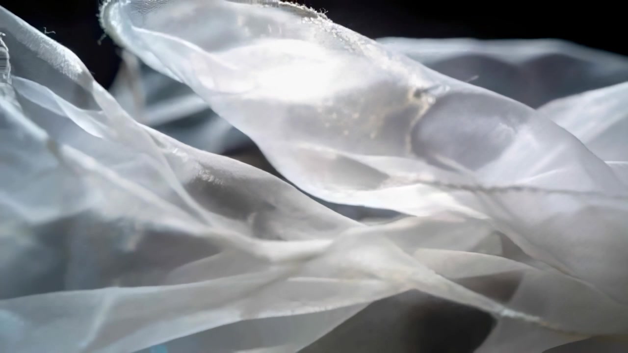 Swaying from fan breeze, sheer fabric moving in studio, backlit to reveal seamed edges and glitter