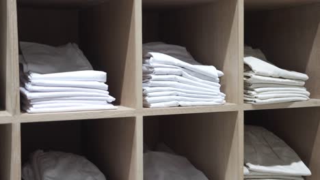 stacked white clothes on wooden shelves