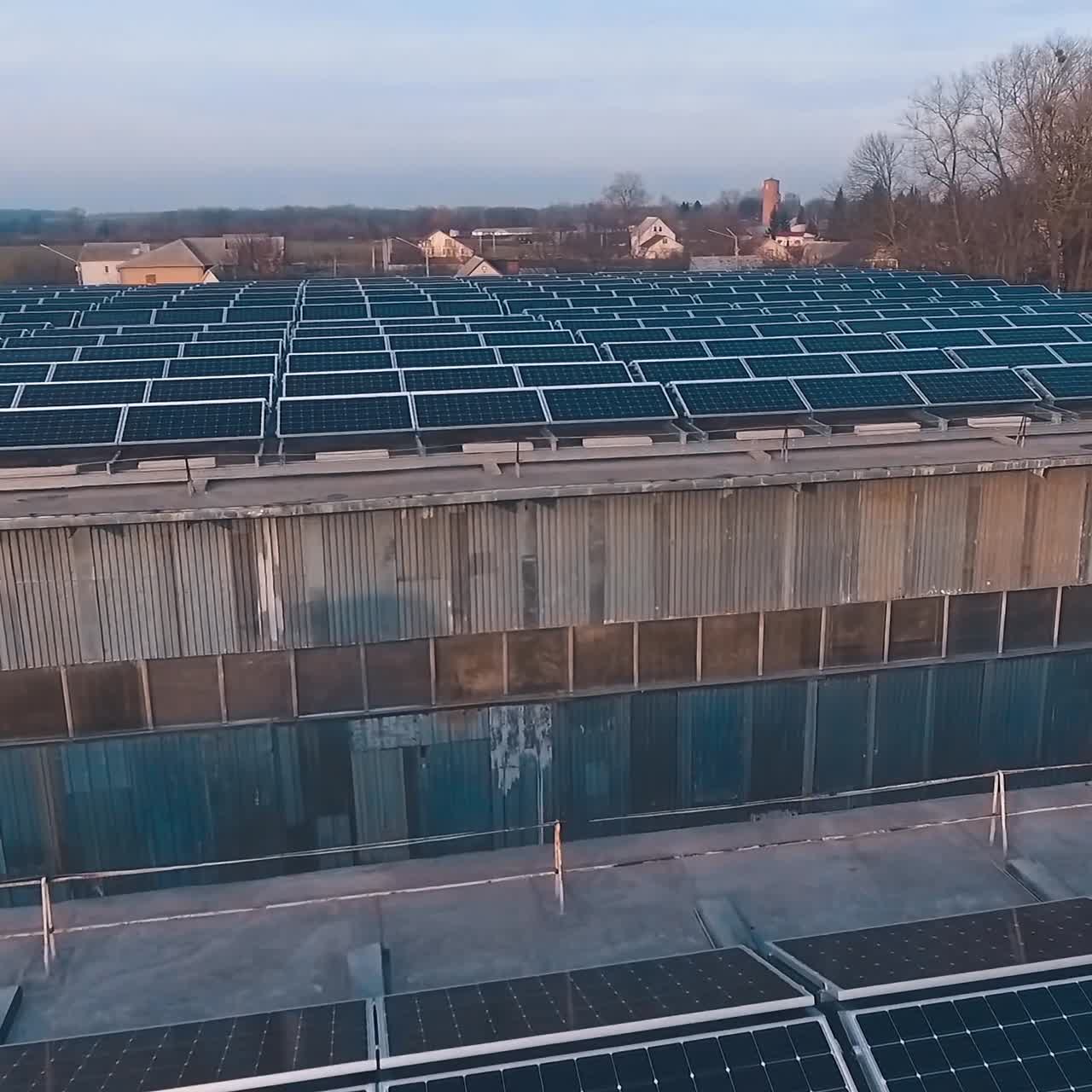 Flight over solar panels farm. Photovoltaic system on the roofs of buildings. Renewable source of green energy from the sun. Drone view.