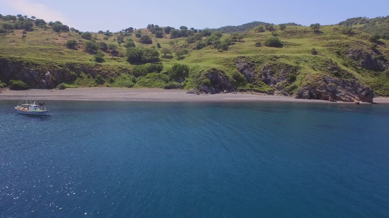 Aerial: A quiet beach with a fishing boat on Lesbos, near Turkey