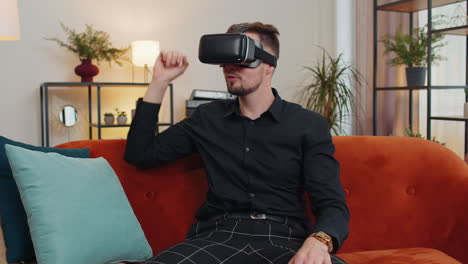 Young-guy-use-virtual-reality-headset-glasses-at-home,-enjoying-video-concept-moving-hands-in-air