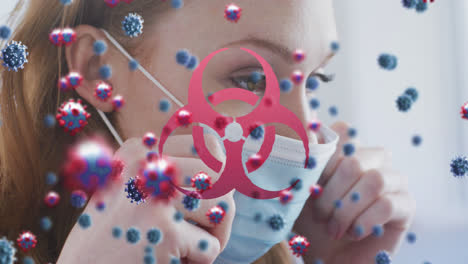 animación de células de virus y símbolo de peligro biológico sobre mujer caucásica con máscara facial