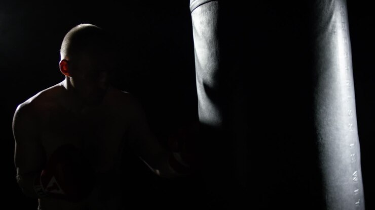 Uomo che si allena nella boxe con un sacco da boxe