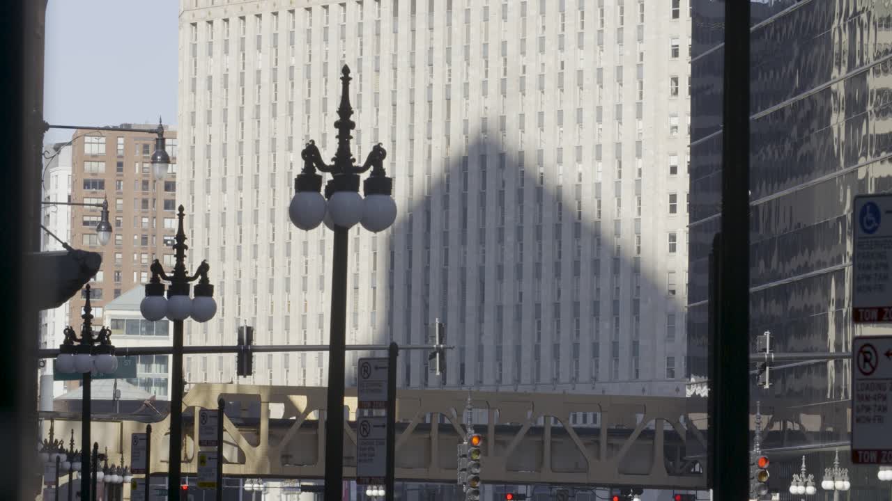 Wide shot: Steady static camera captures the city of Chicago on a sunny day, featuring lamps, skyscrapers, and the railroad