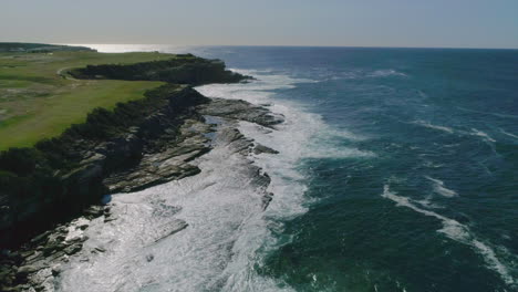 aerial moving shot of little bay as waves onto coastline