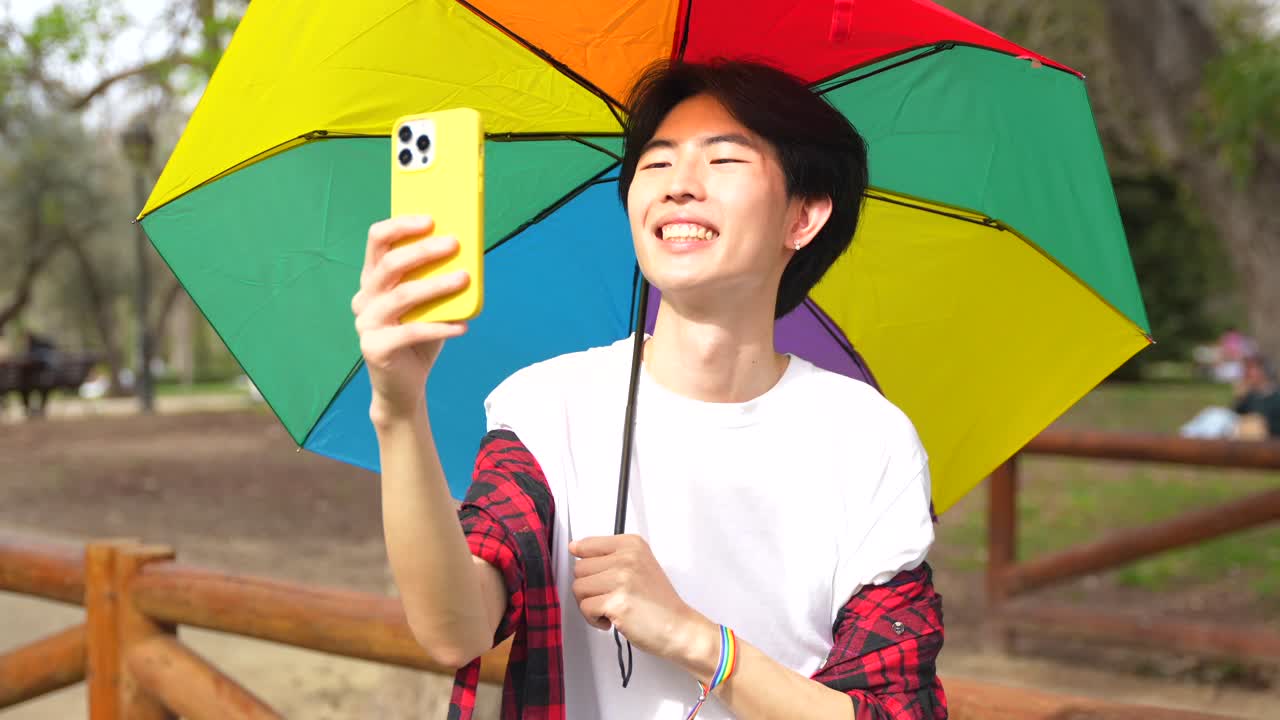 Young Asian Man Taking Selfie with Rainbow Umbrella