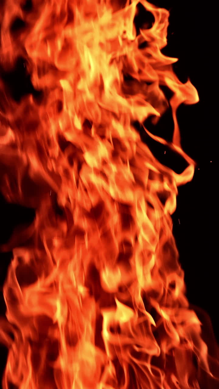 Hot dangerous fire burning at night. Close look at the campfire isolated at black background. Vertical video