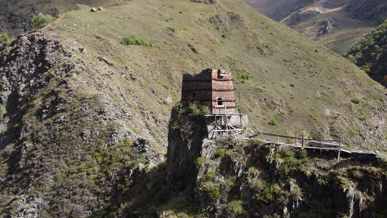 Amazing drone fly to the ancient half fortified stone tower standing on rocky cliff on Mutso village mountain environment, Khevsureti, Mtskheta-Mtianeti, Georgia