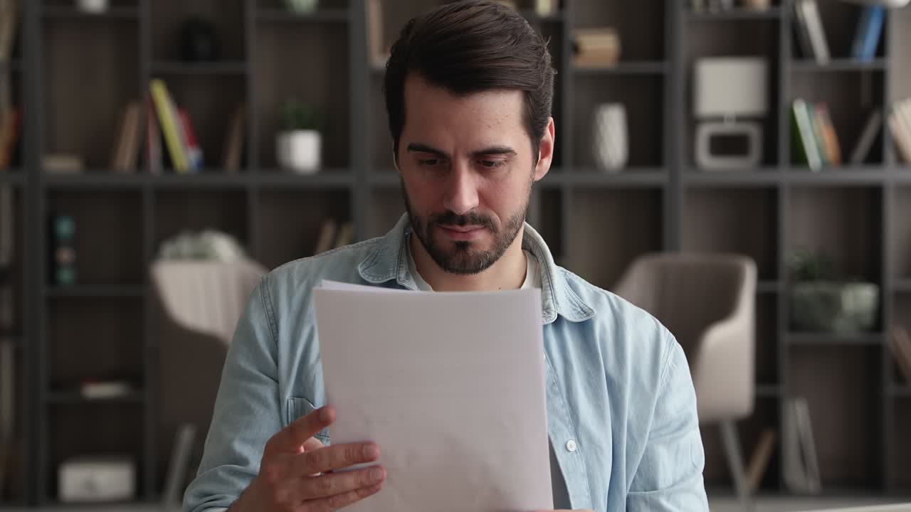 Handsome young caucasian man reading paper letter.