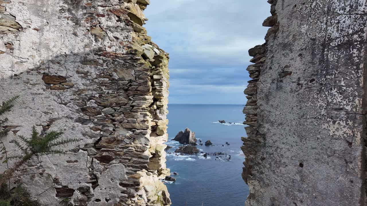 Slow-motion view through ancient stone ruins overlooking the blue ocean