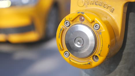 yellow pedestrian button on city street with cars in background