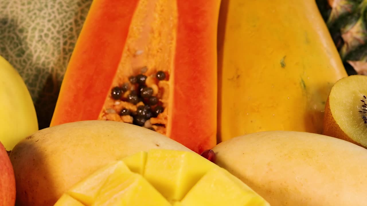 A vibrant display of papaya, mango, pineapple, and cantaloupe in a colorful arrangement.