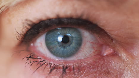 close up studio shot of mature woman opening eye at camera