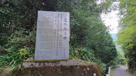 Plakette-Mit-Japanischer-Schrift-Darauf-Neben-Dem-Straßenrand-Im-Wald