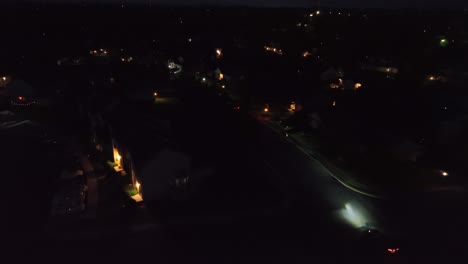 aerial tracking of cars on dark street of housing area in usa. quiet american neighborhood at night with lighting lanterns. flashing bright xenon headlights.
