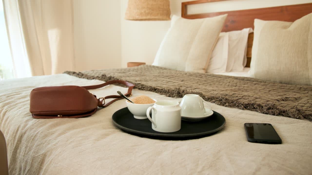 Coffee and smartphone on bed with handbag, creating cozy morning atmosphere, at home