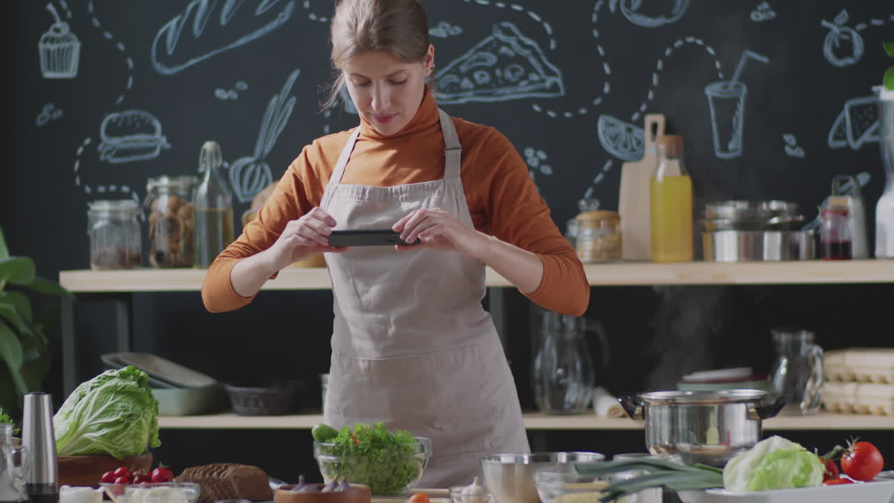 mujer cocinando y tomando fotografías de comida en la cocina