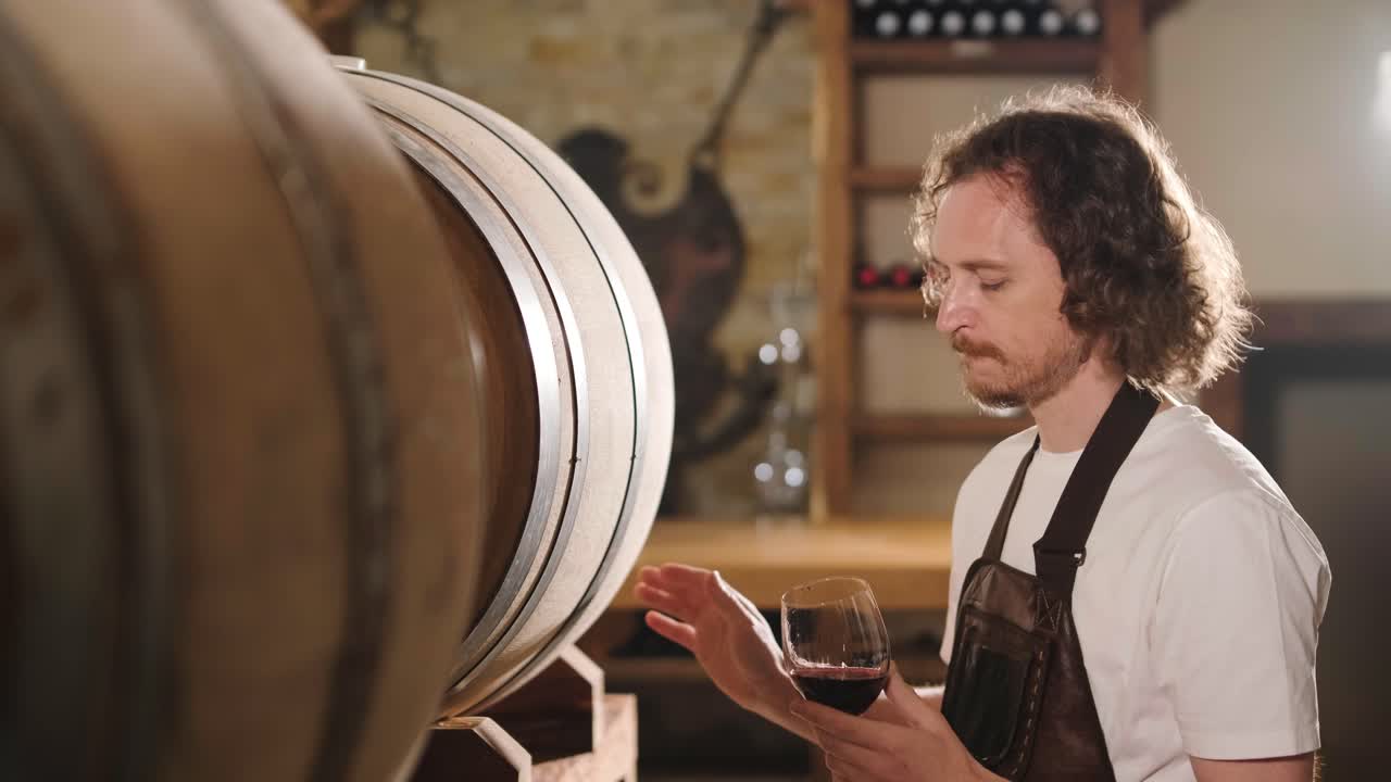 la toma auténtica de un sommelier masculino exitoso es degustar un sabor y comprobar la calidad del vino blanco vertido en vidrio transparente en una bodega de vino.