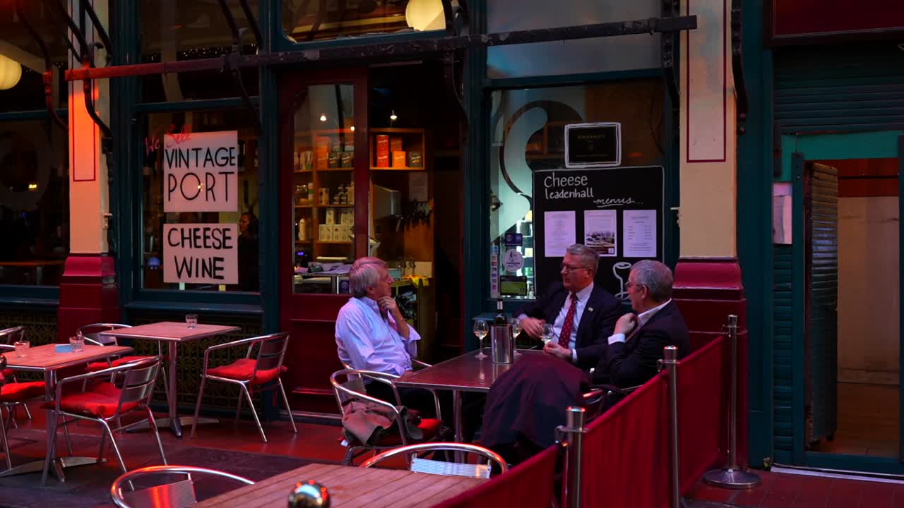 Businessmen enjoy wine outdoors at Leadenhall Market in London after a workday gathering