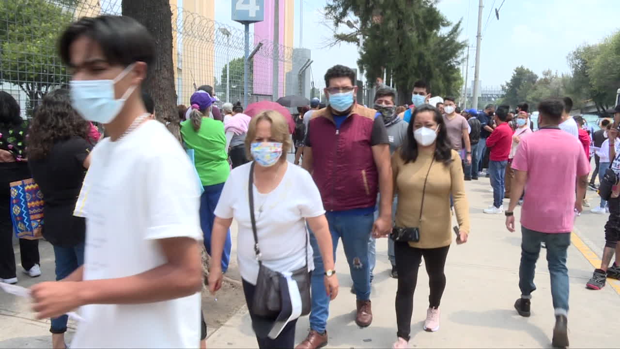 gran grupo de mexicanos con máscaras caminando por la calle