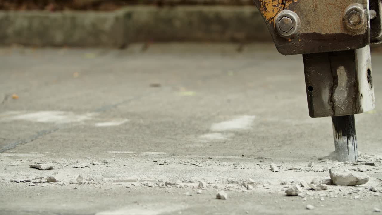 Close-up of excavator hydraulic arm rock breaker working on concrete road