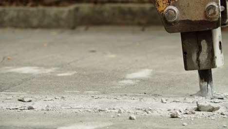 close-up of excavator hydraulic arm rock breaker working on concrete road