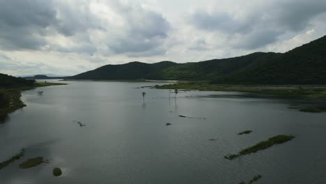 Absteigende-Luftaufnahmen-Des-Sees,-Schöner-Sonnenuntergang-Und-Horizont,-Regenwolken-Und-Berge,-Weiter-Blick-Auf-Das-Wasser-Und-Die-Palmen,-Muak-Klek,-Saraburi,-Thailand