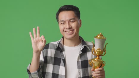 man holding a trophy and making an ok sign