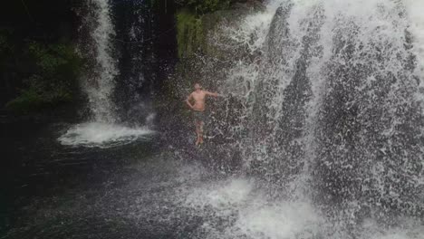 man showers under natural waterfall