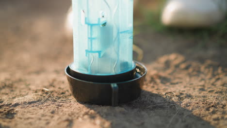 primer plano de un recipiente de plástico en el suelo con algo de hierba en el fondo, probablemente utilizado para alimentar o regar a los animales. escena al aire libre con luz natural que destaca los detalles del recipiente