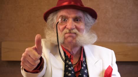 Older-man-with-nice-beard-puts-in-monocle-and-gives-a-thumbs-up-to-camera