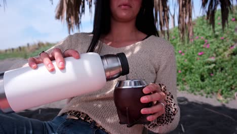 mujer joven bebiendo mate en la playa, pichilemu punta de lobos chile, sirviendo mate, cámara lenta, primer plano