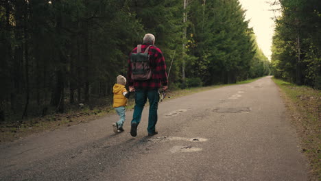 viejo pescador y su pequeño nieto están caminando a pescar en la mañana de fin de semana abuelo está llevando mochila y caña