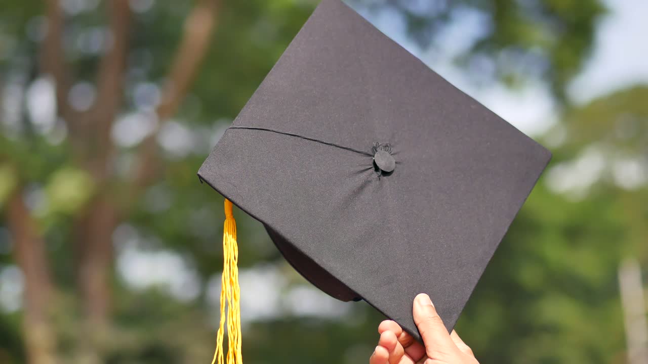 los estudiantes sostienen los sombreros en la mano durante el éxito de la graduación