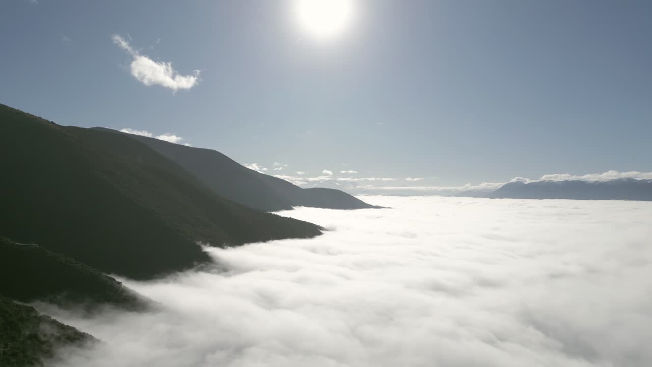 Aerial drone footage gliding over endless stratus clouds, revealing a serene, soft white blanket stretching to the horizon with peak mountains breaking through.