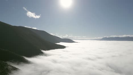aerial drone footage gliding over endless stratus clouds, revealing a serene, soft white blanket stretching to the horizon with peak mountains breaking through.