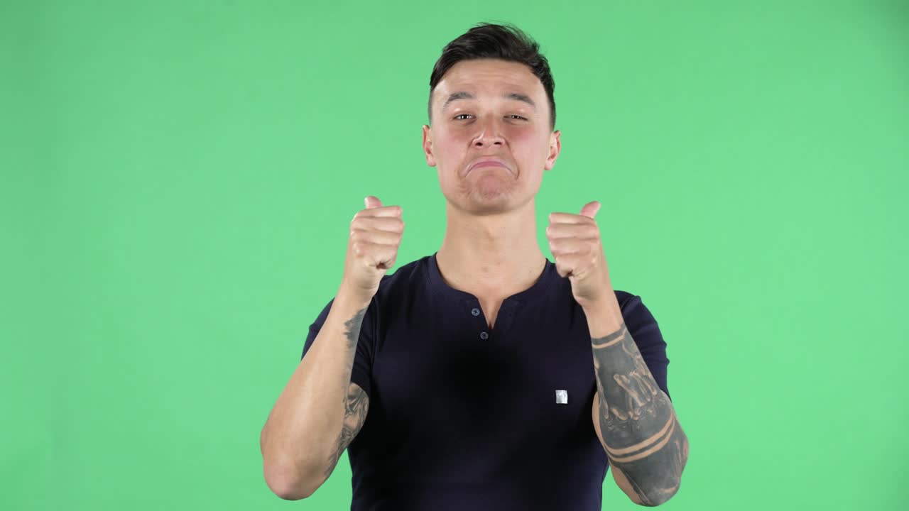 잘생긴 젊은 남자의 초상화가 카메라를 바라보고 엄지손가락을 보여주고 있습니다. 녹색 화면