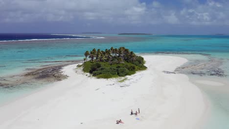 Sobrevuelo-Aéreo-Bajo-Y-Lento-De-Una-Pequeña-Isla-Arenosa-Con-Palmeras-Y-Vegetación-Verde