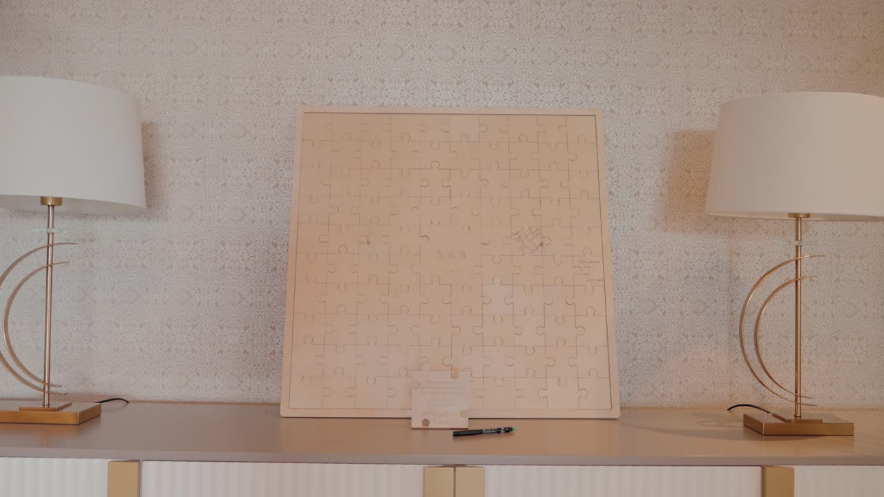 wooden puzzle guestbook displayed on a table between two lamps, with a pen ready for signatures
