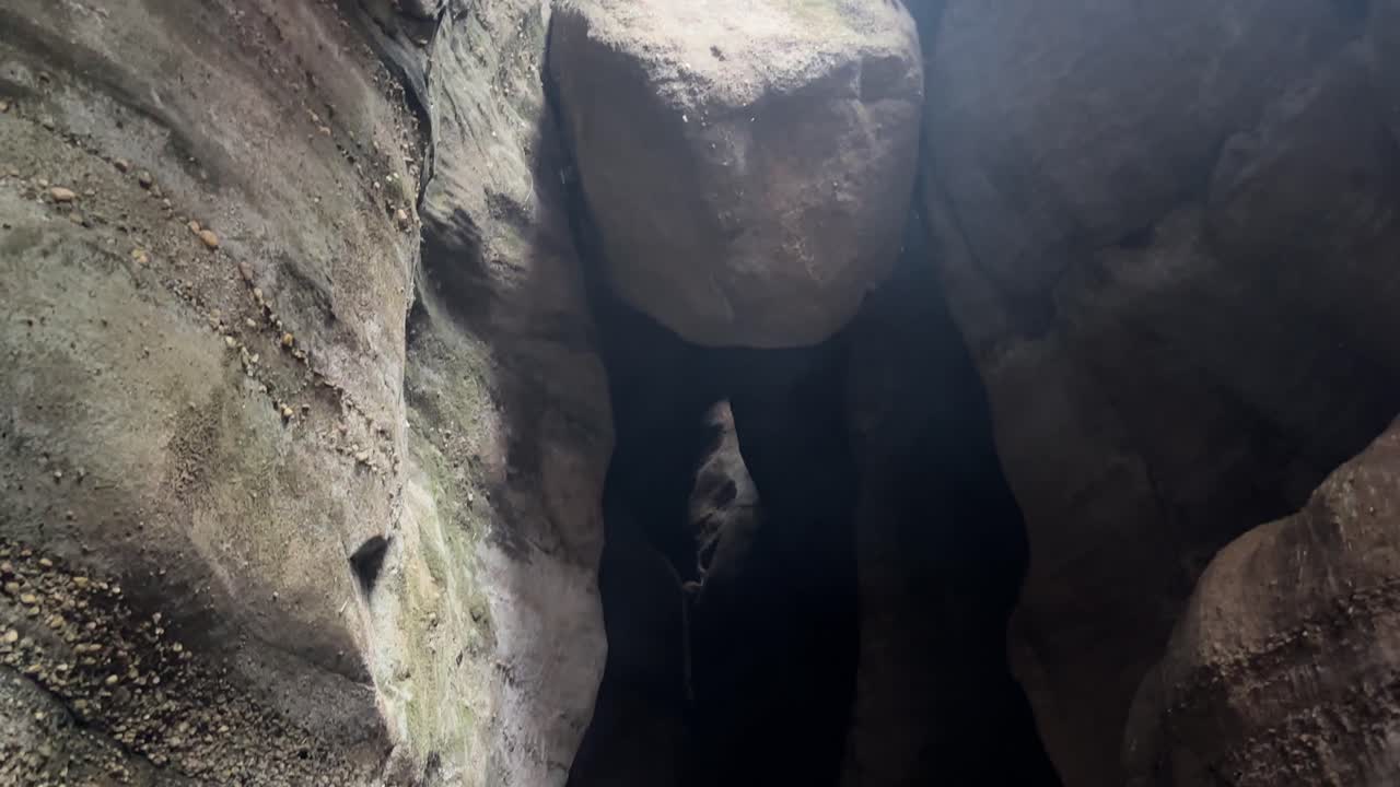 Narrow opening in cave illuminates lake with tip of Lord Shiva's trident visible. Tilt down