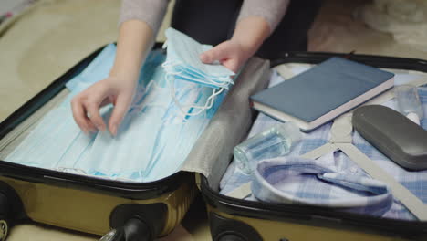 a woman packs clothes and face mask for a business trip 5