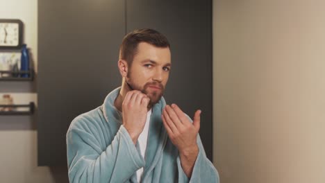 un hombre bien arreglado se pone y se peina la barba con un peine