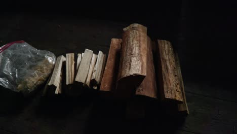 a slow panning shot of a pile of wooden logs for firewood, chopped kindling and firelighters in a plastic bag