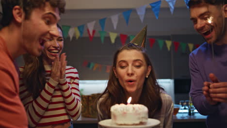 Friends surprising birthday girl bringing cake close up. Amazed woman blowing