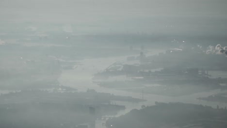 Aerial-view-over-industrial-city-in-smog-with-river-and-factories