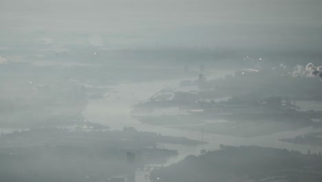 aerial view over industrial city in smog with river and factories